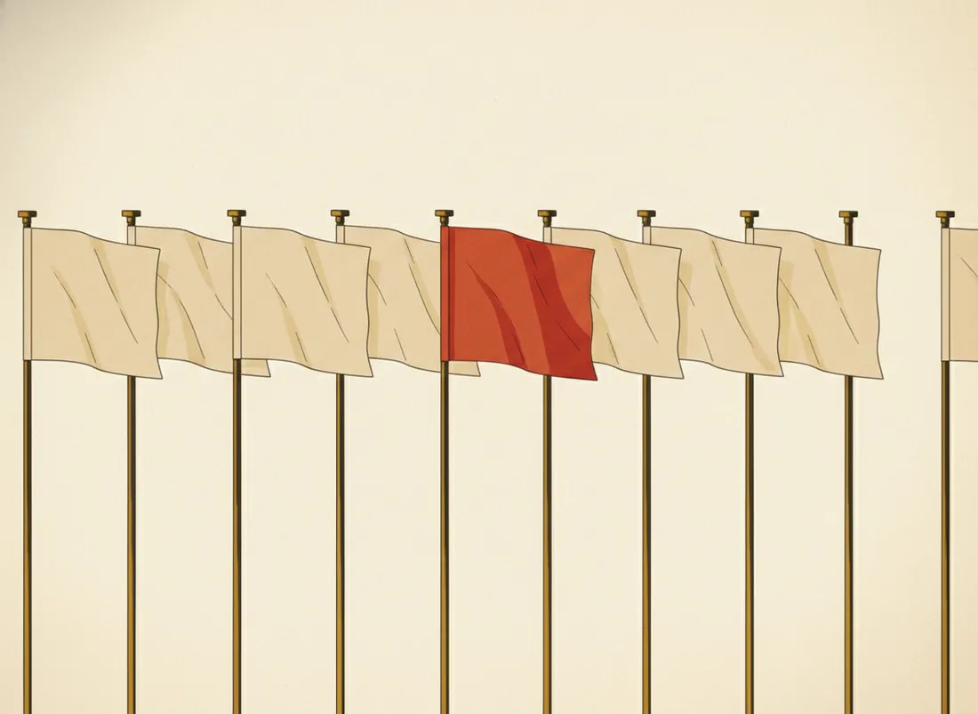 A red flag planted among a row of identical white flags